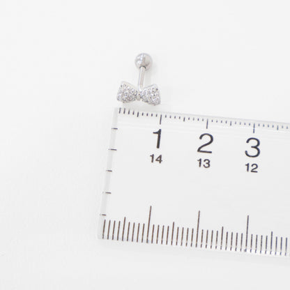 Silver bow barbell earring placed next to a ruler, showing approximate width of 1.3 cm