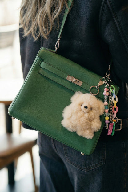 Giant alpaca teddy keychain attached to green leather handbag luxury styling