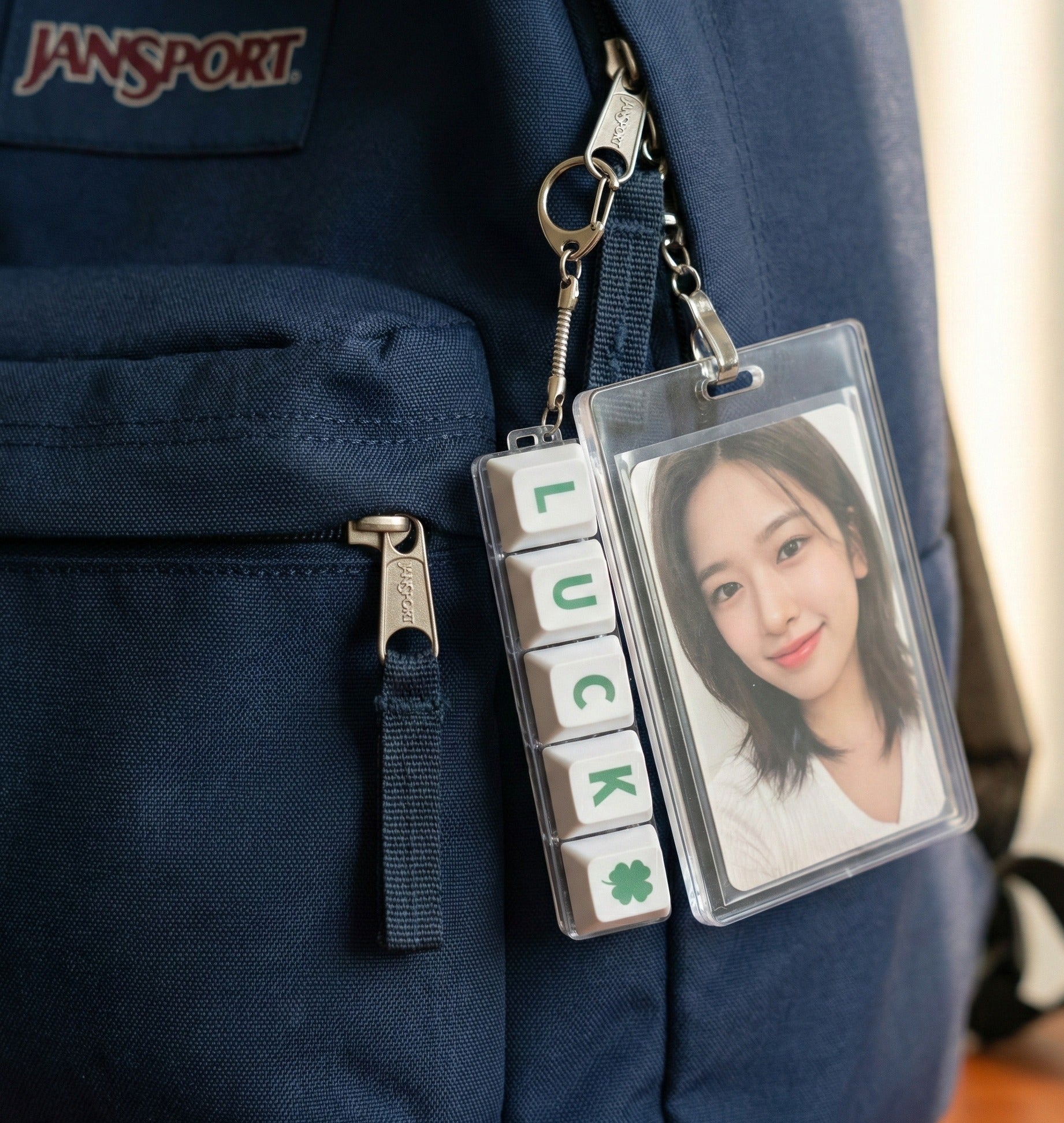 LUCK keychain hanging from green backpack strap with idol photocard holder