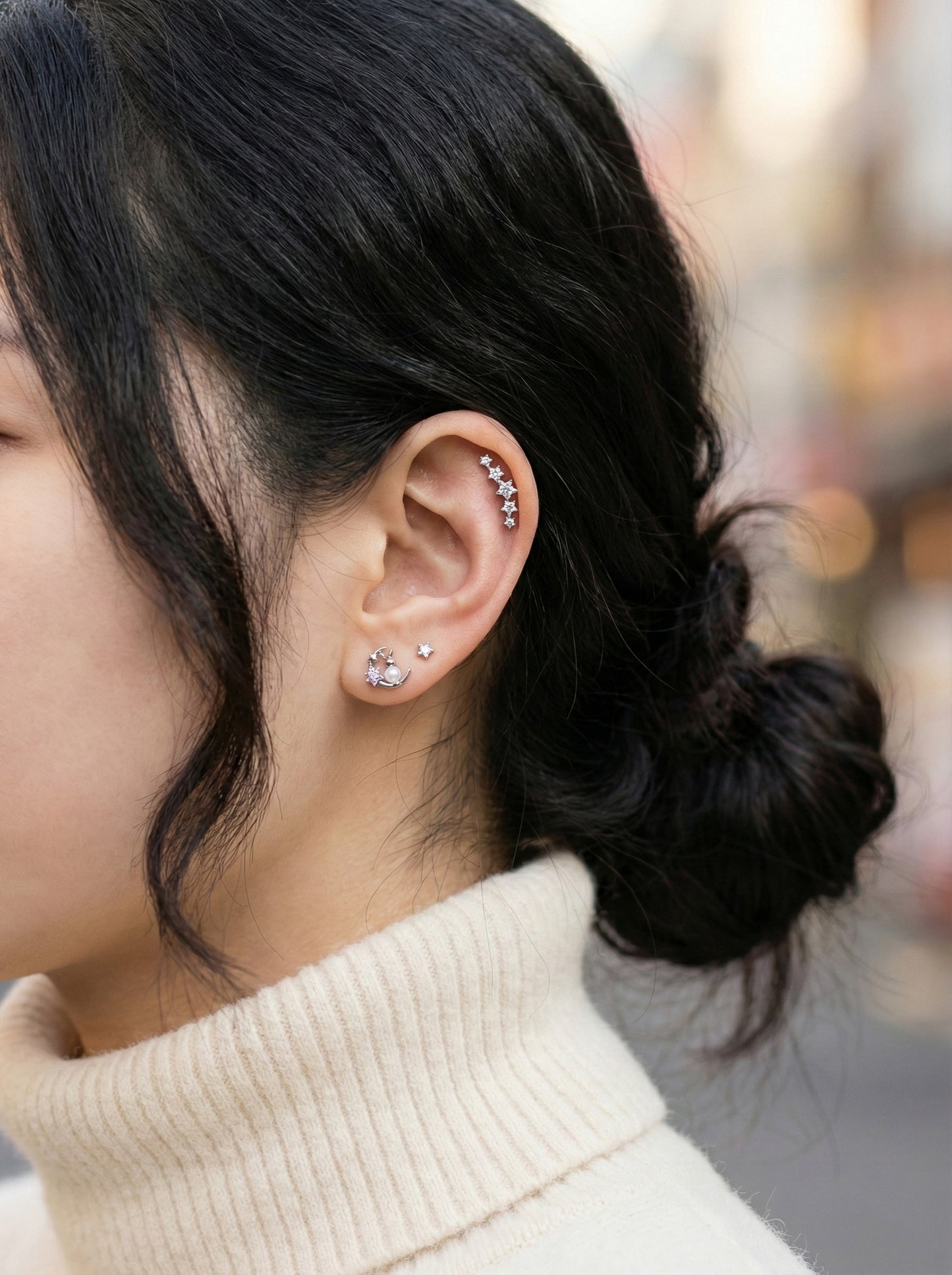 Multiple cartilage piercings styled together featuring moon rabbit earring with CZ line in helix