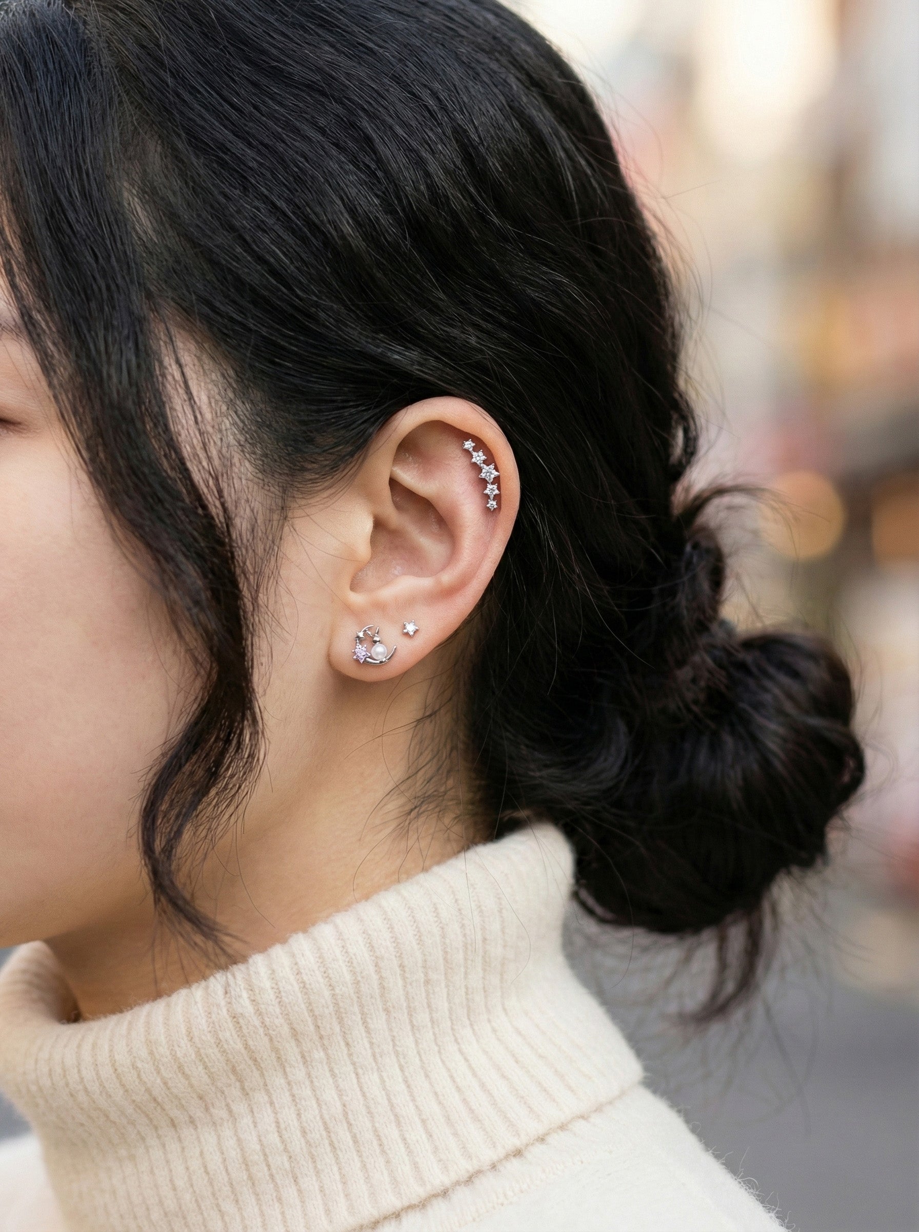 Multiple cartilage piercings styled together featuring moon rabbit earring with CZ line in helix
