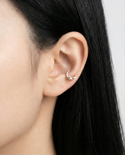Zoomed-out view of rose gold moon cartilage piercing with a sparkling finish on a minimalist ear styling.