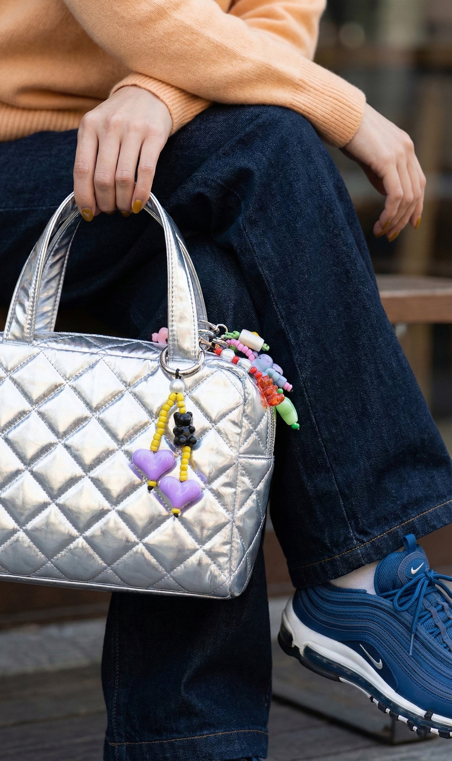  Purple and yellow heart beaded bag charm with black bear on silver quilted handbag and blue sneakers