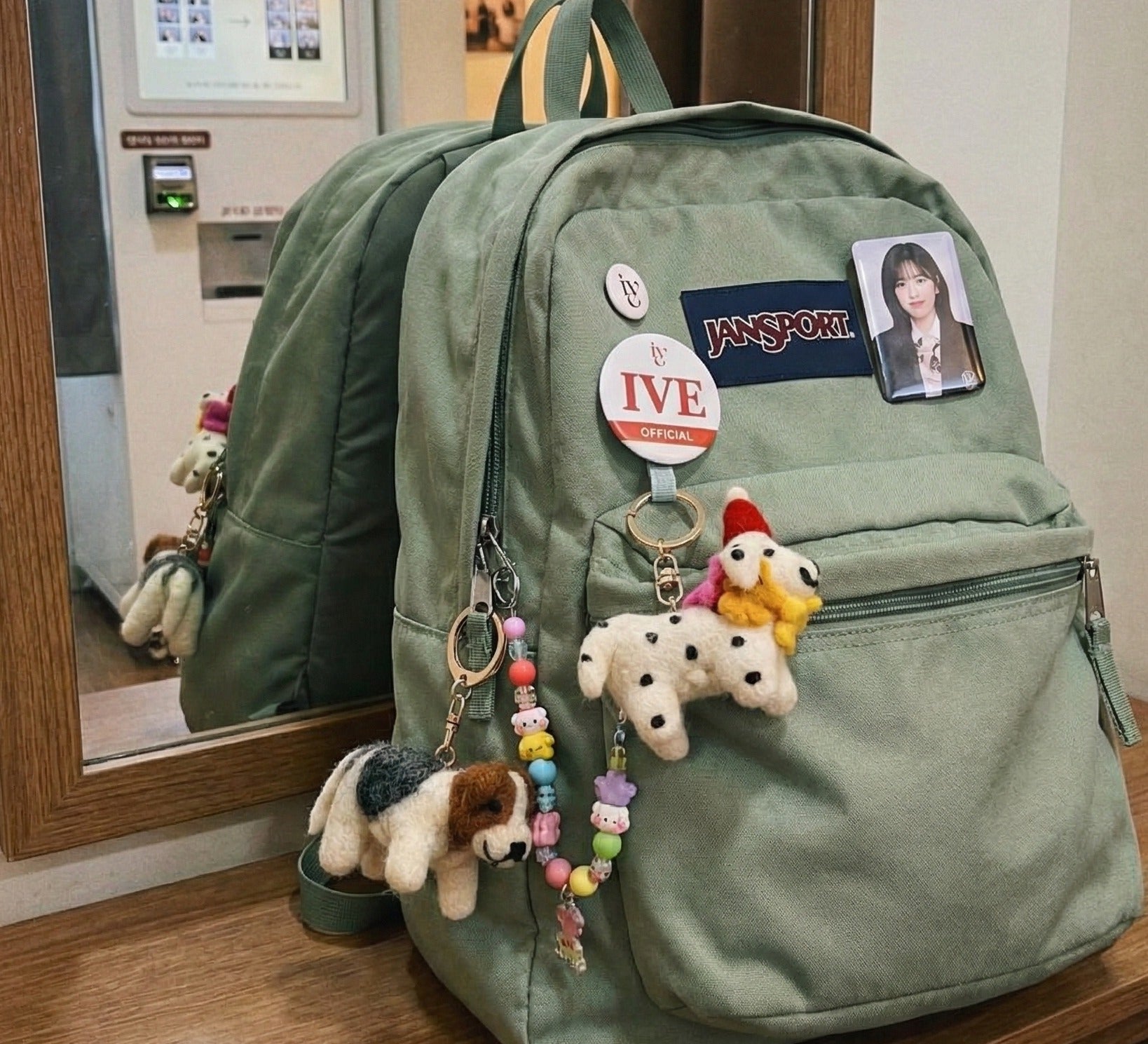 Green Jansport backpack decorated with wool felt Dalmatian and Terrier keychains and colorful bead chains