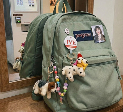 Green Jansport backpack decorated with wool felt Dalmatian and Terrier keychains and colorful bead chains