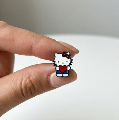 Close-up of Heart Hug Hello Kitty stud with vibrant red heart and blue overalls, premium enamel coating