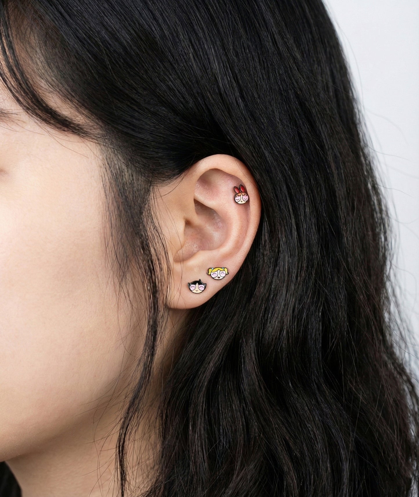 Full ear styling with three Powerpuff Girls barbell studs - layered on lobe outer conch and helix piercings