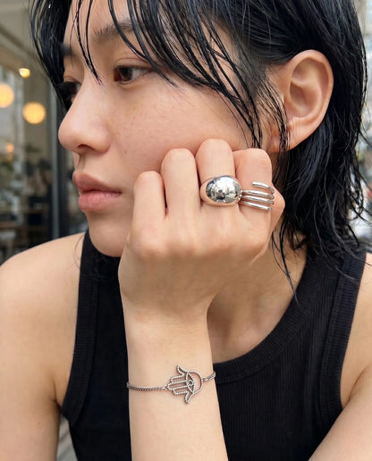 K-street jewelry stack inspo 8ttitto8 dome ring triple band ring with hamsa silver bracelet, sleeveless black top grunge look.