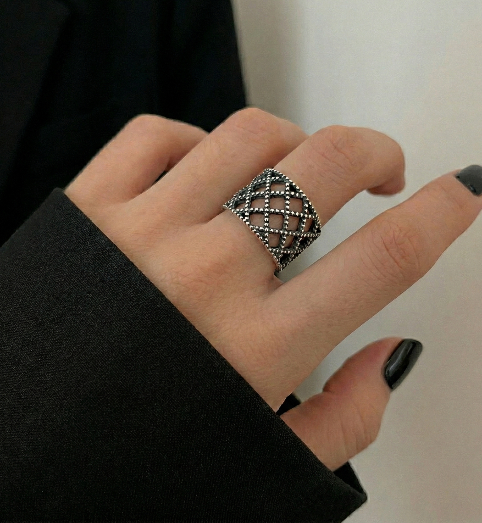 925 sterling silver lace lattice ring worn on middle finger against black jacket sleeve, bold antique oxidized wide band ring, statement jewelry close-up
