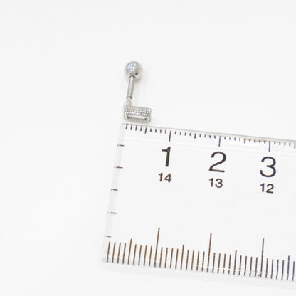 Side view of a silver rectangular CZ barbell earring next to a ruler for size reference.