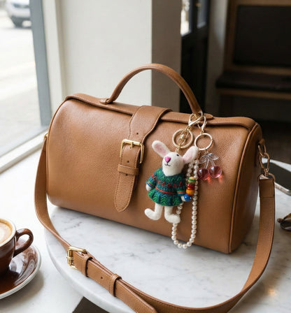 Brown leather handbag on cafe table with handmade bunny keychain and pearl strap accessory