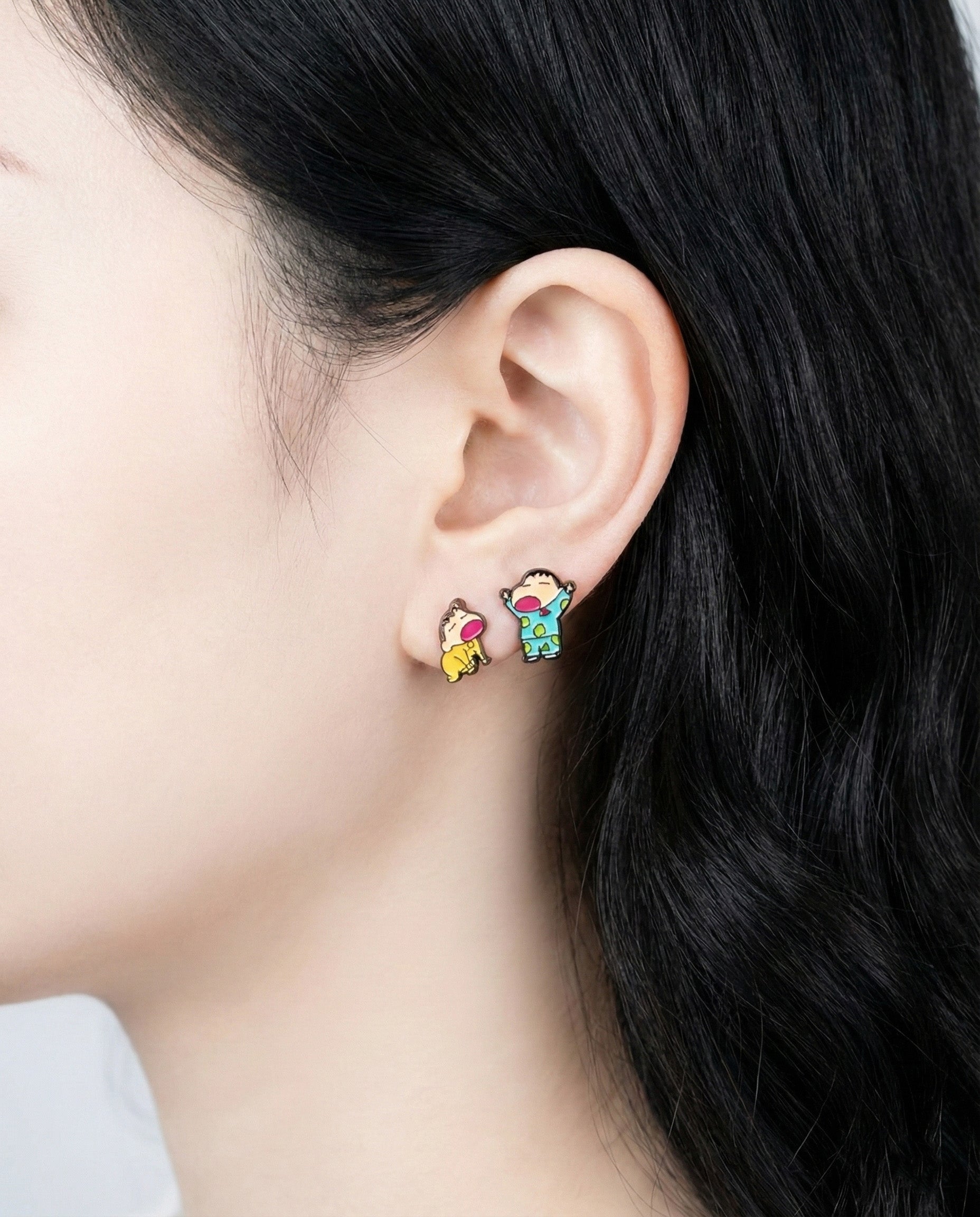 Close-up of Shin-chan and Himawari pajama earrings showing detailed enamel work on model's ear