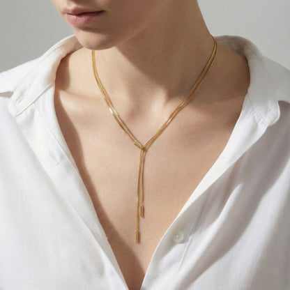 Elegant gold Y-drop necklace with two chain rows, styled with a crisp white shirt