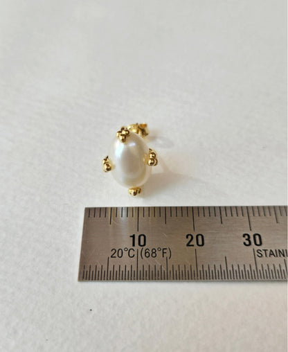 Single gold oval pearl stud earring next to a ruler for size measurement.