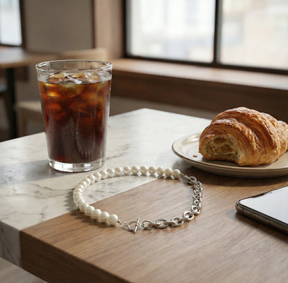Lifestyle shot of silver pearl chain choker on cafe table with croissant and iced coffee