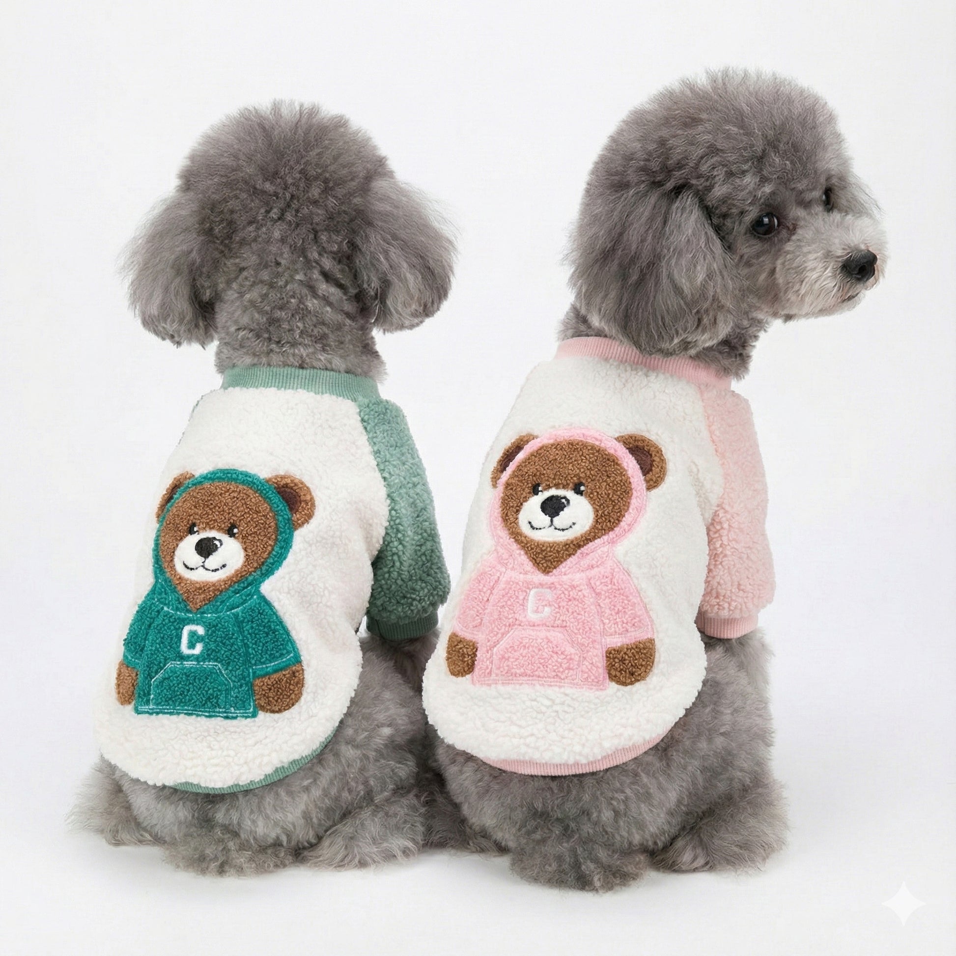 Front view of two gray poodles wearing mint and pink bear character fleece shirts