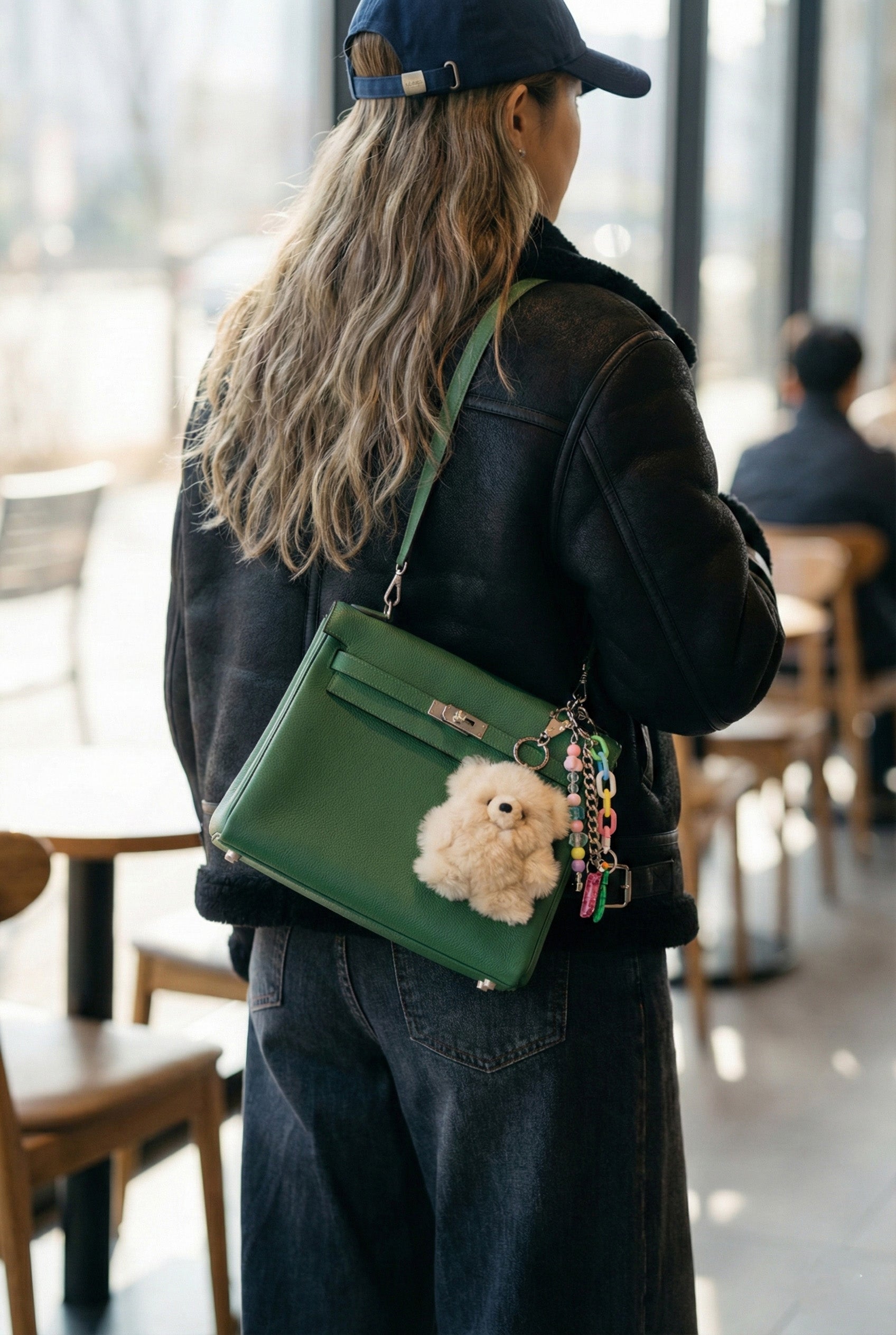 Woman carrying bag with oversized real alpaca fur keychain statement accessory