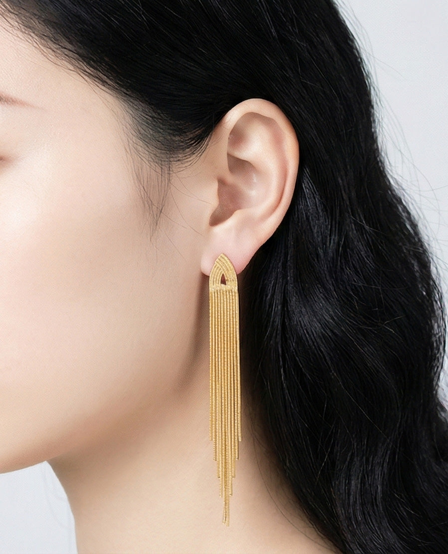 Woman wearing 10cm gold chain tassel drop earrings, elegant long fringe statement jewelry