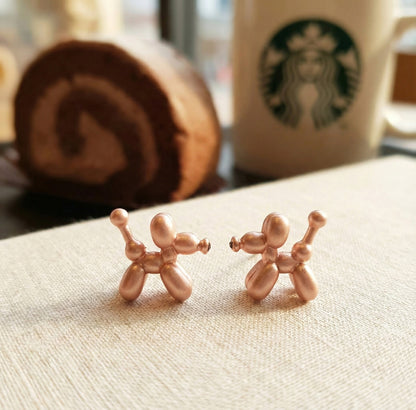 Rose gold balloon dog earrings with soft metallic finish on neutral background