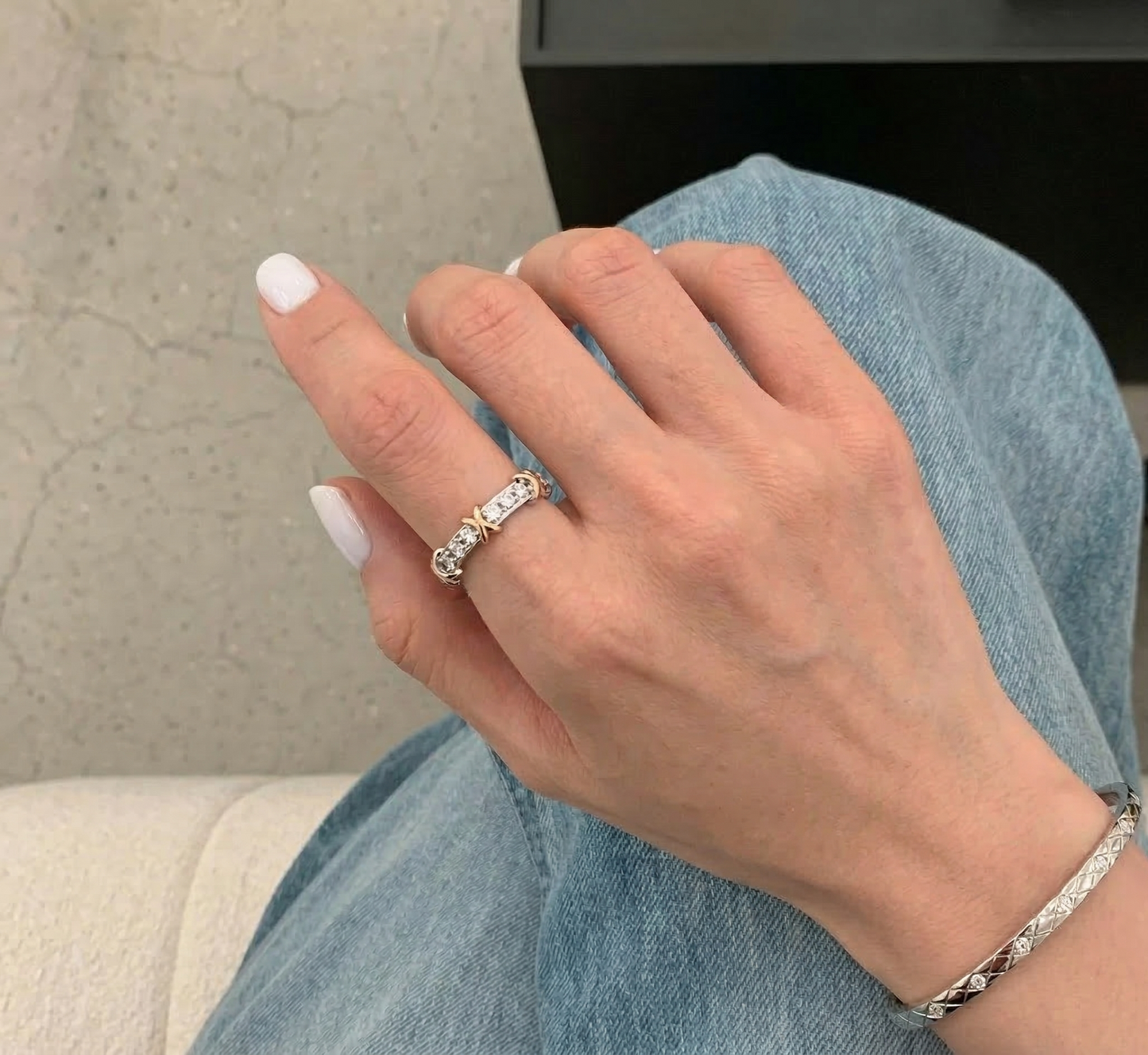 Lifestyle shot of the two-tone cubic zirconia X-cross ring worn with a silver chain bracelet against a denim outfit — casual layering inspiration