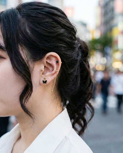 Gold chain piercing with black butterfly and rose stud worn on ear with casual hairstyle