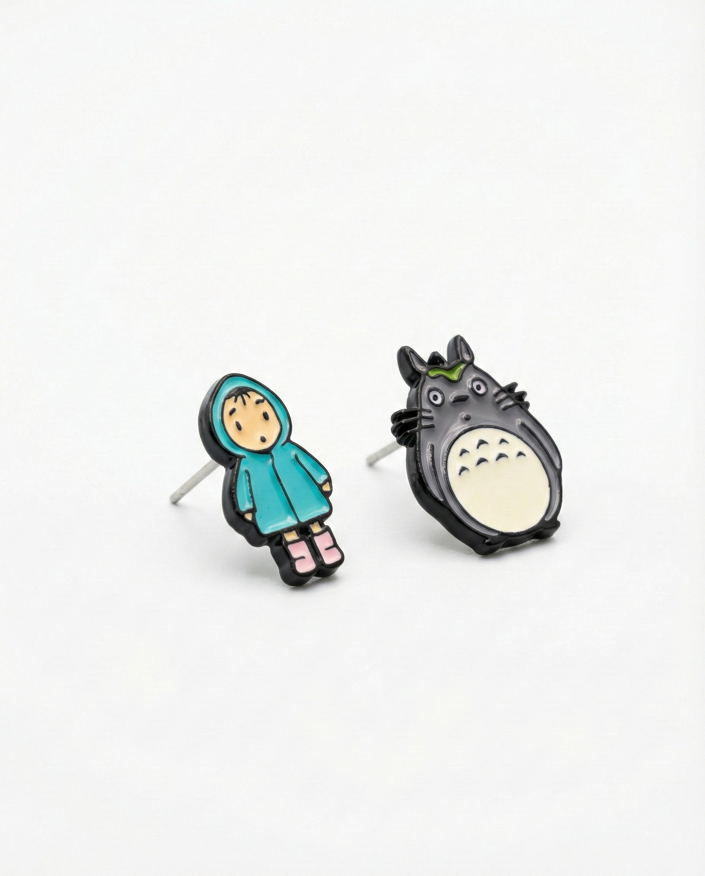 Detailed close-up of hand-painted Totoro and raincoat Mei brass stud earrings with silver posts