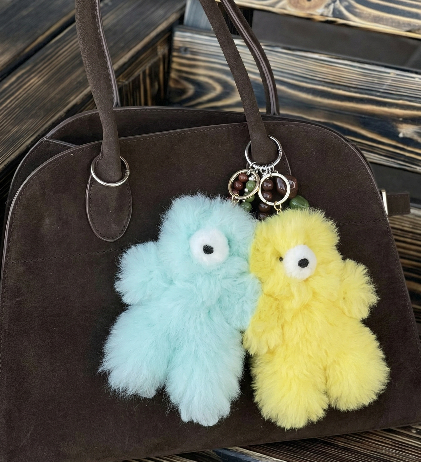 Mint and yellow-green alpaca bear plush keyrings attached to a dark brown suede dome bag with beaded charm decorations