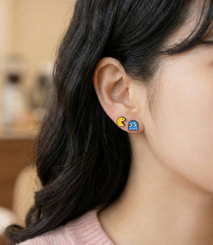 Woman wearing two earrings — red Blinky ghost stud and yellow Pac-Man stud — for a simple mismatch retro kawaii look