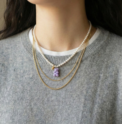 Woman wearing lavender gummy bear pearl necklace with gray sweater - Y2K coquette style