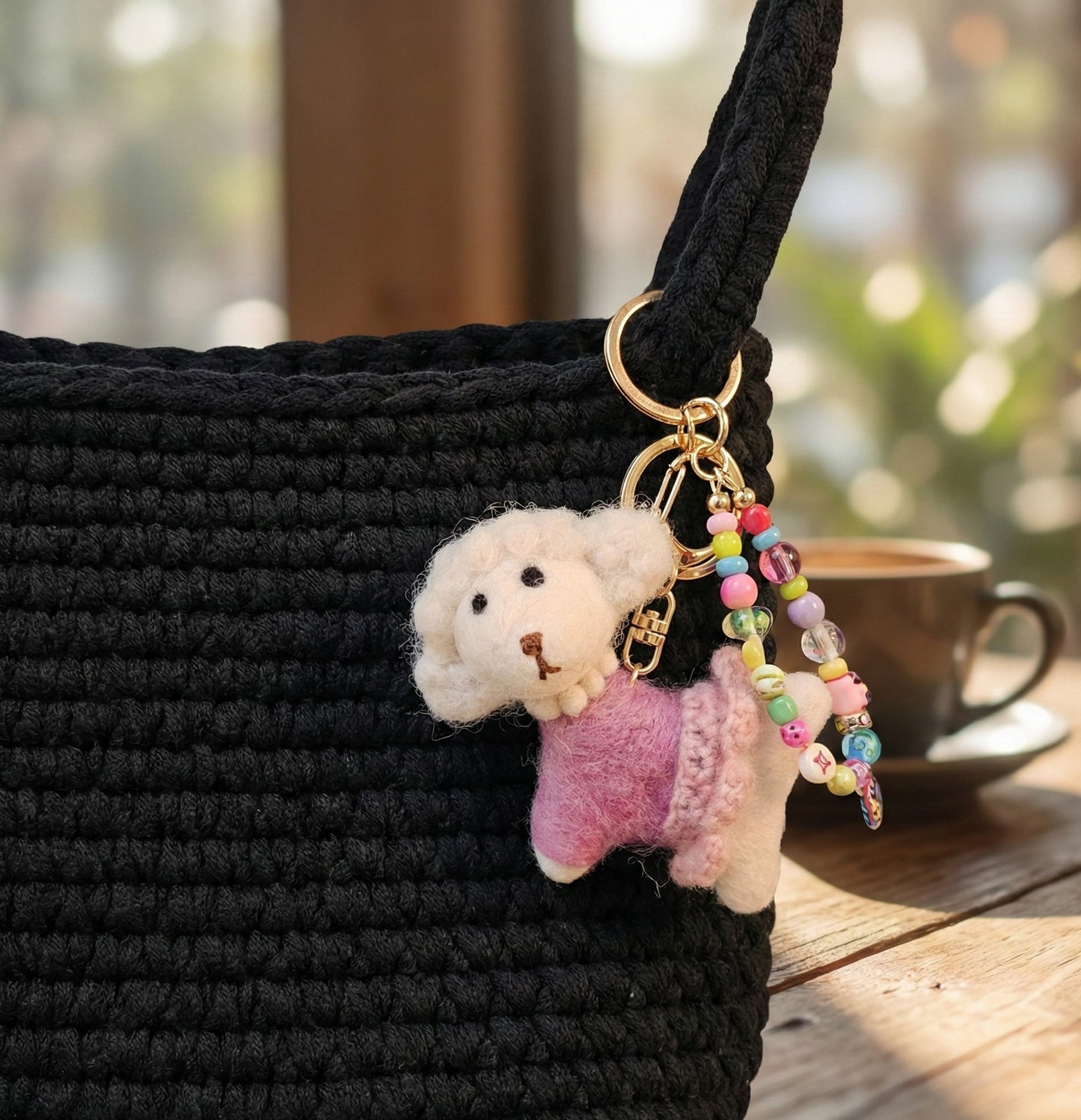 Black crochet bag decorated with wool felt poodle charm and colorful bead keychain at cafe