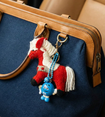 Blue crossbody bag styled with red wool horse charm layered with M&amp;M character figure and blue beads