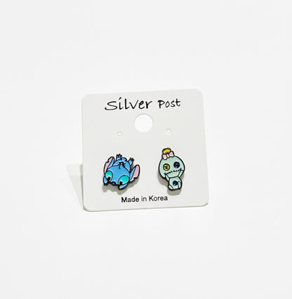 Stitch lying down and Scrump character earrings on a white backing card, pastel enamel finish.
