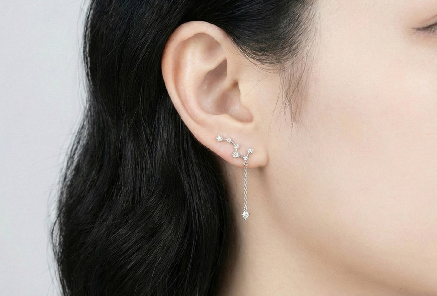 Front view of woman wearing silver constellation earring showing star cluster design along earlobe with single cubic zirconia drop, lightweight comfortable fit, Korean handmade jewelry