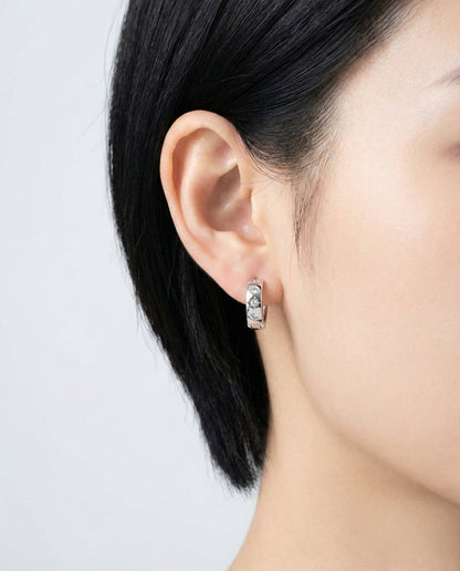 Silver-tone hoop earrings with cubic zirconia stars, worn on the left ear with straight side view.