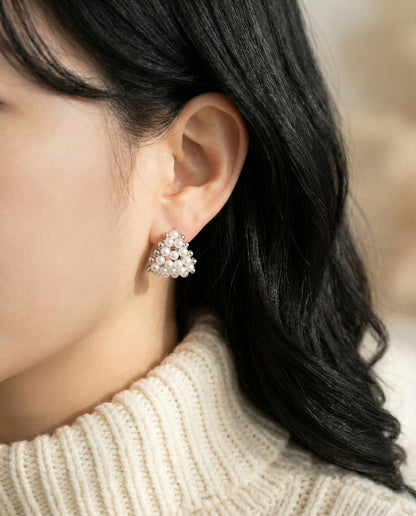 Woman wearing silver pearl heart C-hoop earrings with cream turtleneck - side profile
