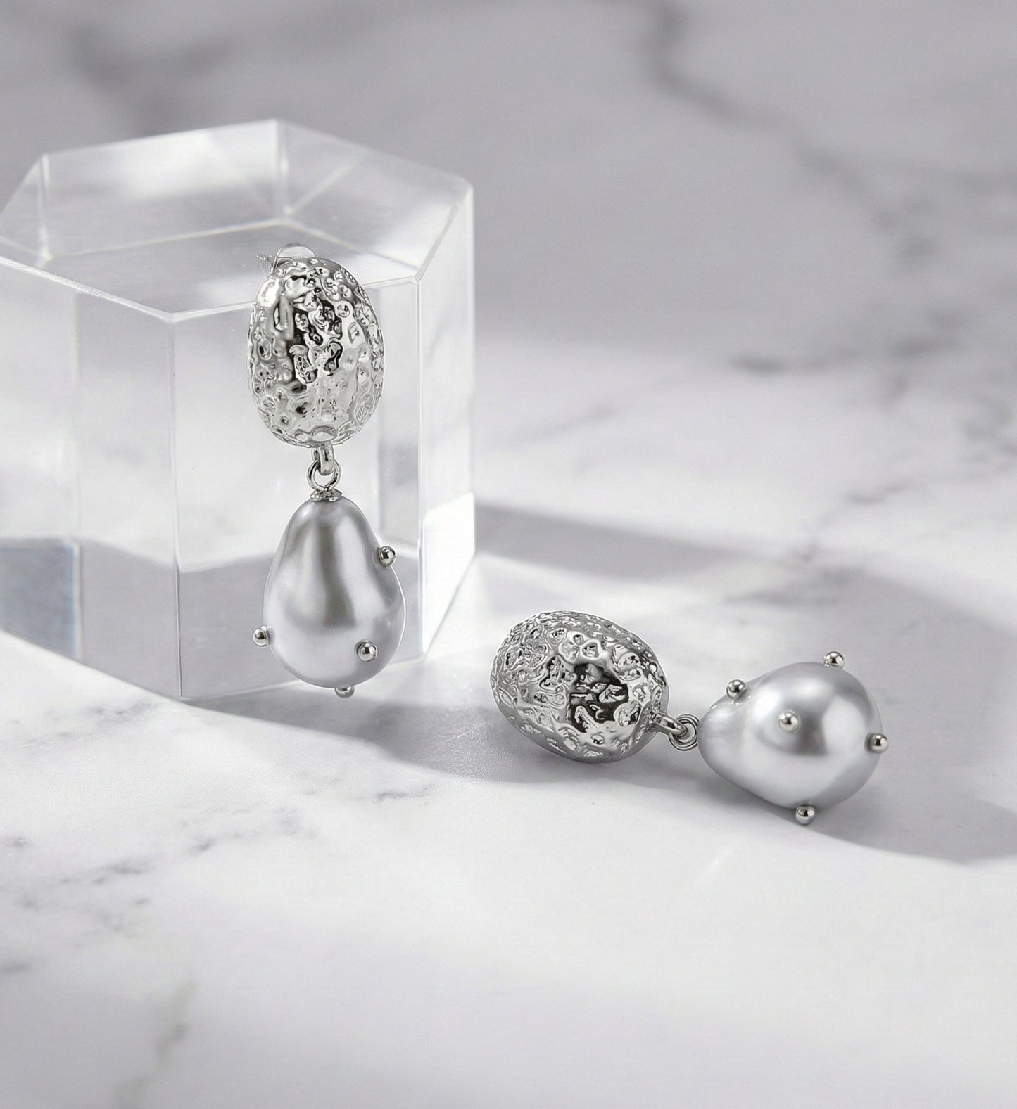 Front view of gold hammered baroque pearl drop earrings on display stand