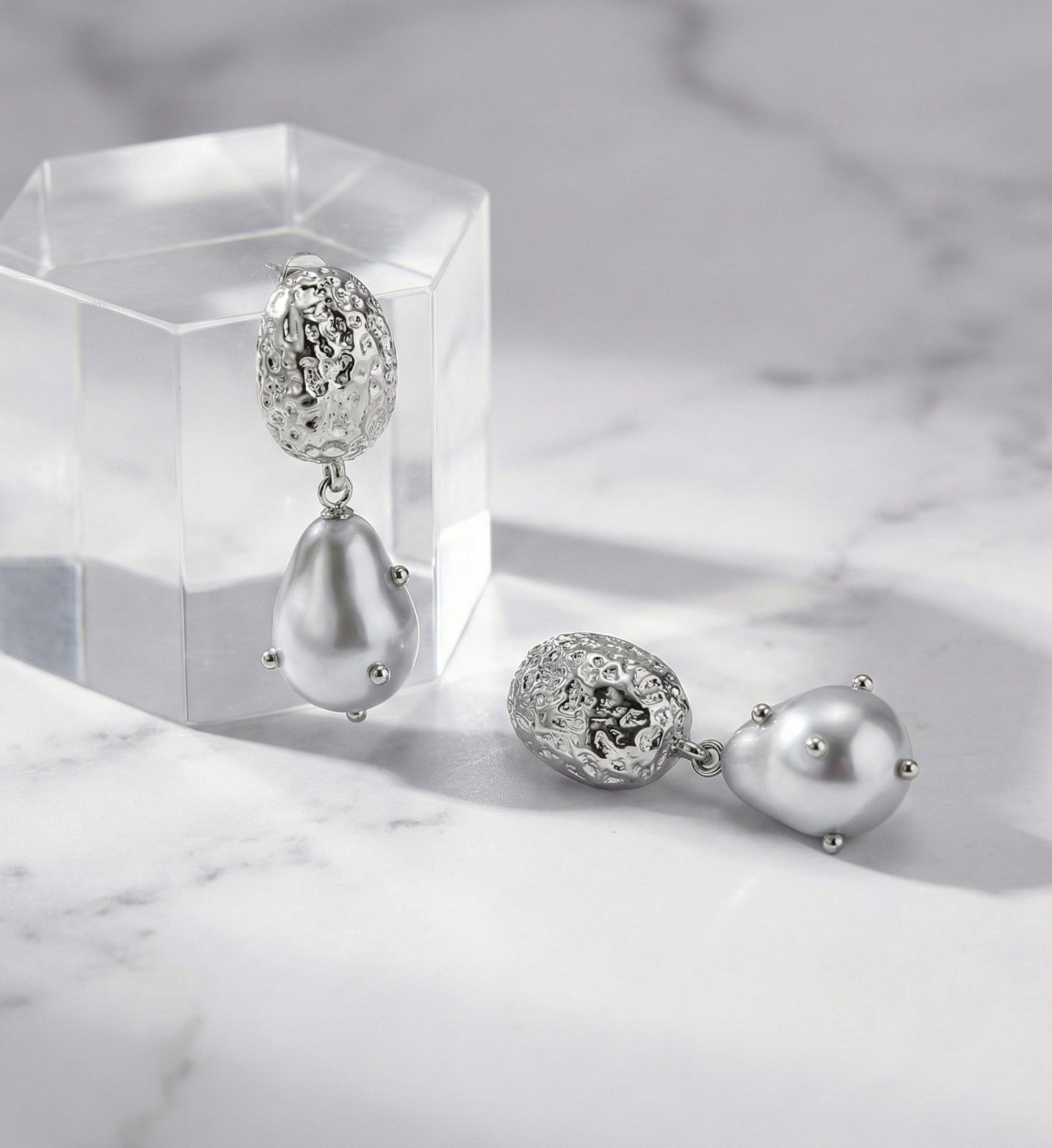 Front view of gold hammered baroque pearl drop earrings on display stand