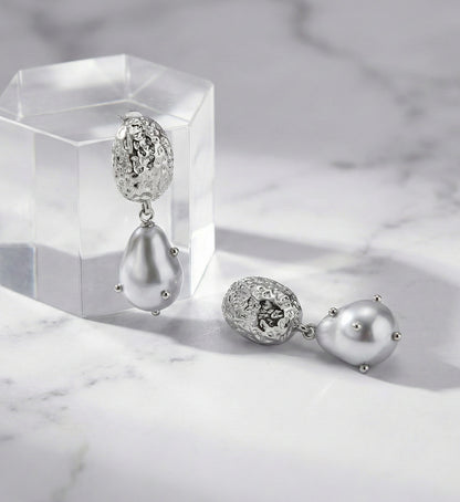 Front view of gold hammered baroque pearl drop earrings on display stand