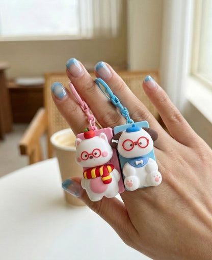 Two chubby animal keycap keychains - pink cat and blue dog with red glasses