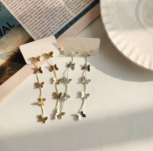 Flat lay of gold and silver butterfly drop earrings on white display cards