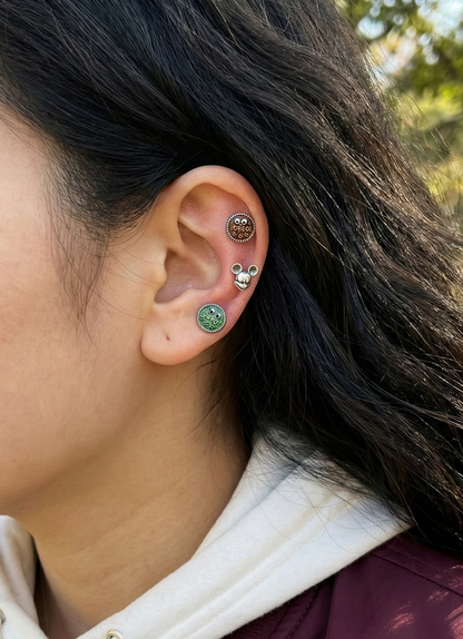 Ear styling with three piercings - brown Oreo on upper cartilage, Mickey on conch, green Oreo on lobe