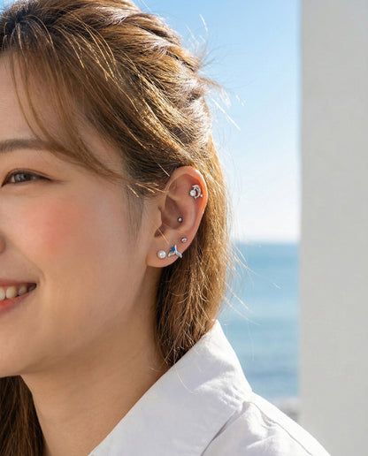 Side profile close-up showing blue cubic zirconia whale tail barbell stud catching sunlight