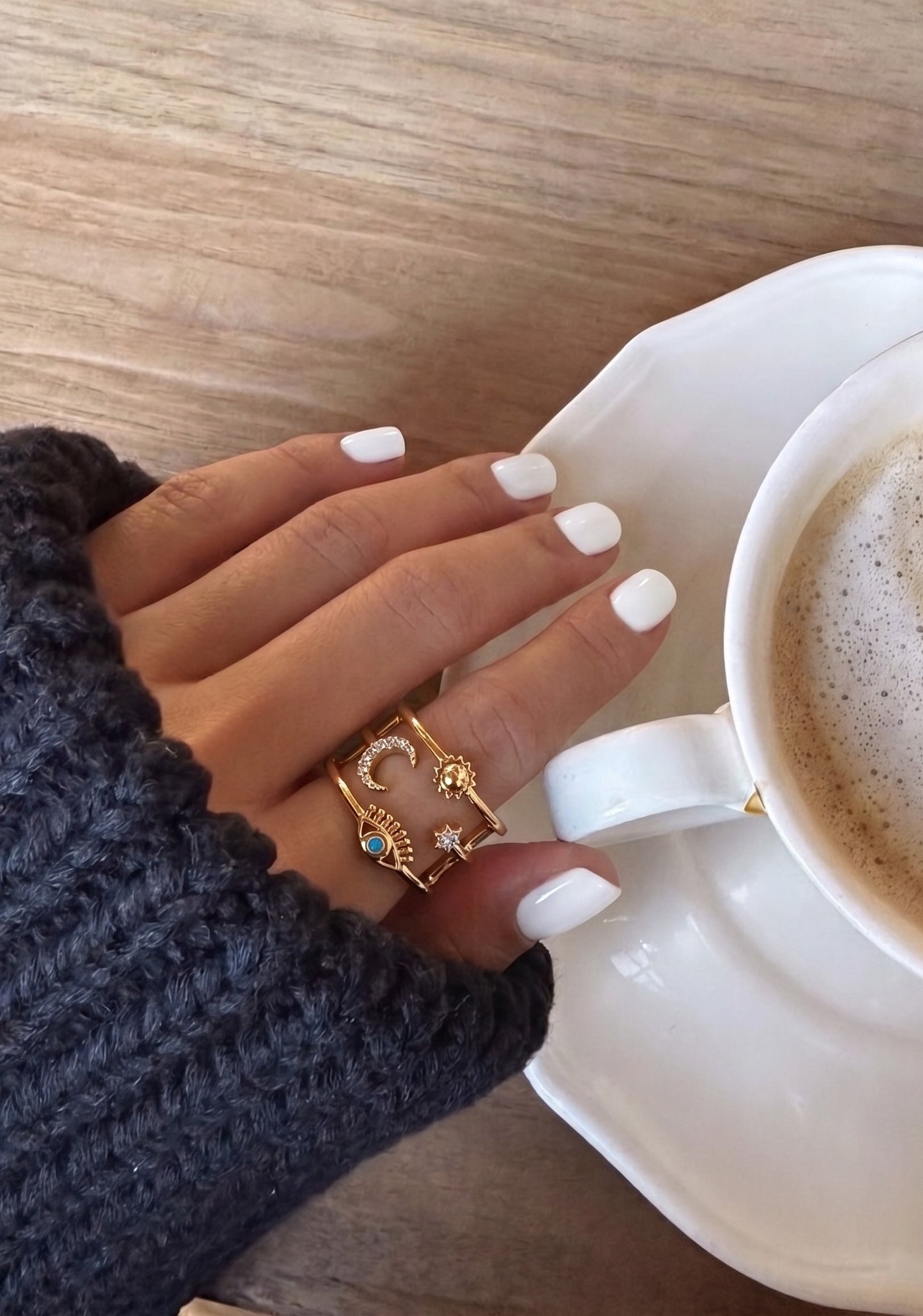  Café selfie aesthetic model wearing silver evil eye sun moon star layered brass ring, K-style daily ring inspo close-up.