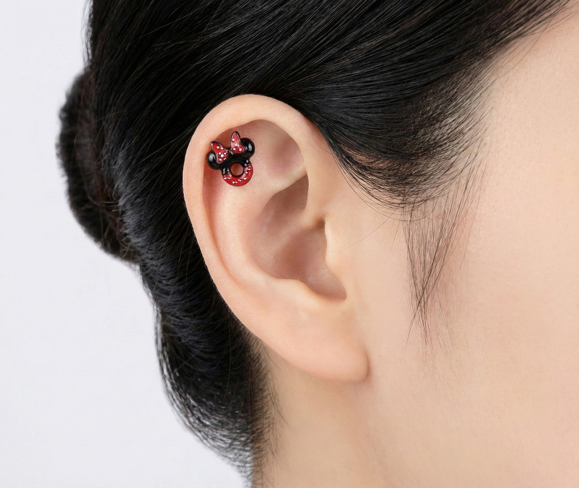 Close-up of a woman wearing a Minnie Mouse themed stud earring on her cartilage.
