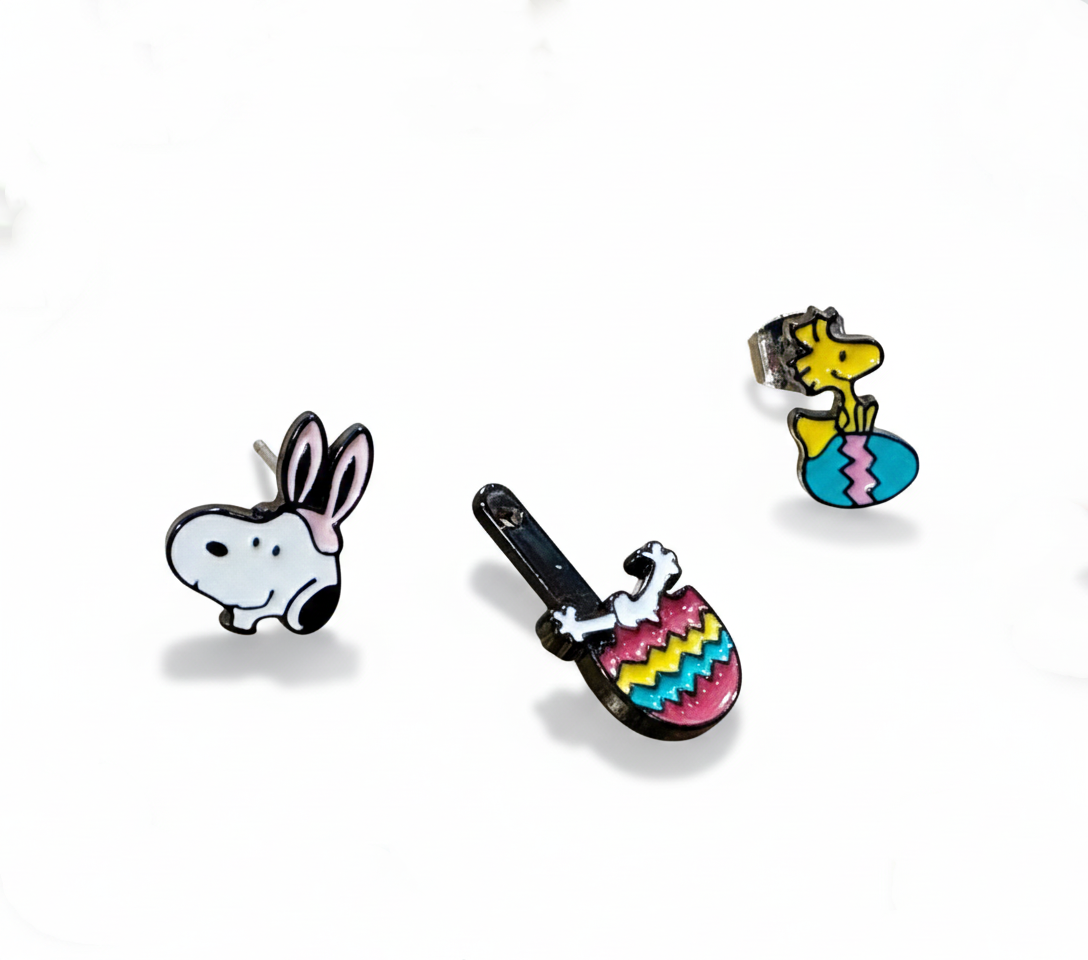 Spring-themed flat lay of Snoopy Woodstock earrings with colorful Easter eggs and bokeh lights