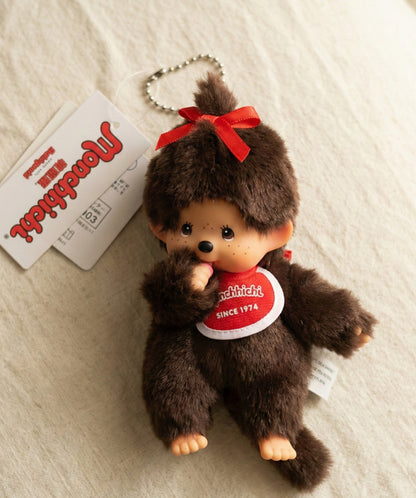 Monchhichi Ribbon Girl plush keychain with red satin bow on linen background with original hang tag — Y2K kawaii bag charm