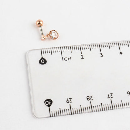 Gold and blue planet barbell earring placed next to a transparent ruler for size reference.
