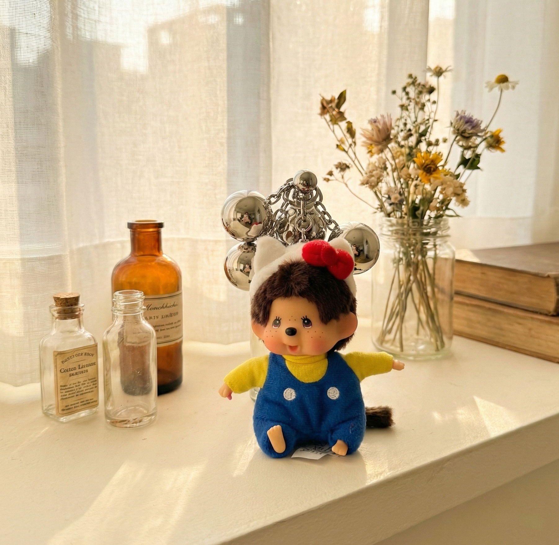Monchhichi Hello Kitty keychain displayed with dried flowers and vintage glass bottles