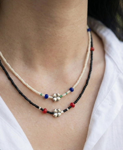 Neck view of woman wearing double-layered ivory and black four-leaf clover seed bead chokers showing choker fit
