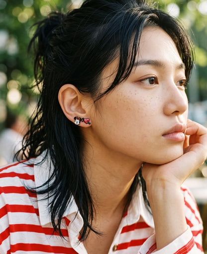 Model side profile wearing mouse face and heart-arrow enamel stud earrings, red stripe OOTD.
